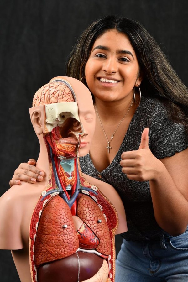 Rachel Lobo, 12, poses with the skeleton from an AP Chemistry classroom. She wishes to pursue a career in medicine in the future.