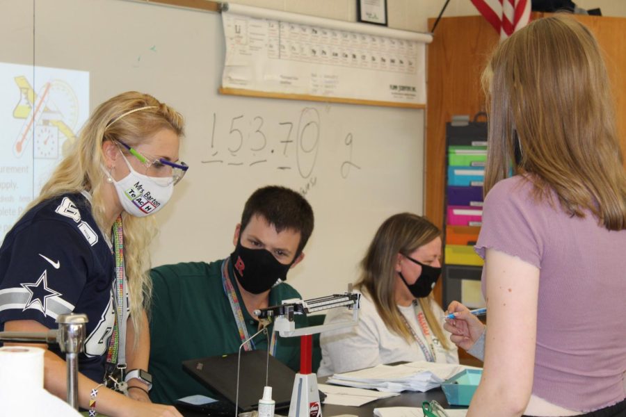Mrs. Barton and Mr. Pike work with students in chemistry class to measure mass during the measurement lab. 