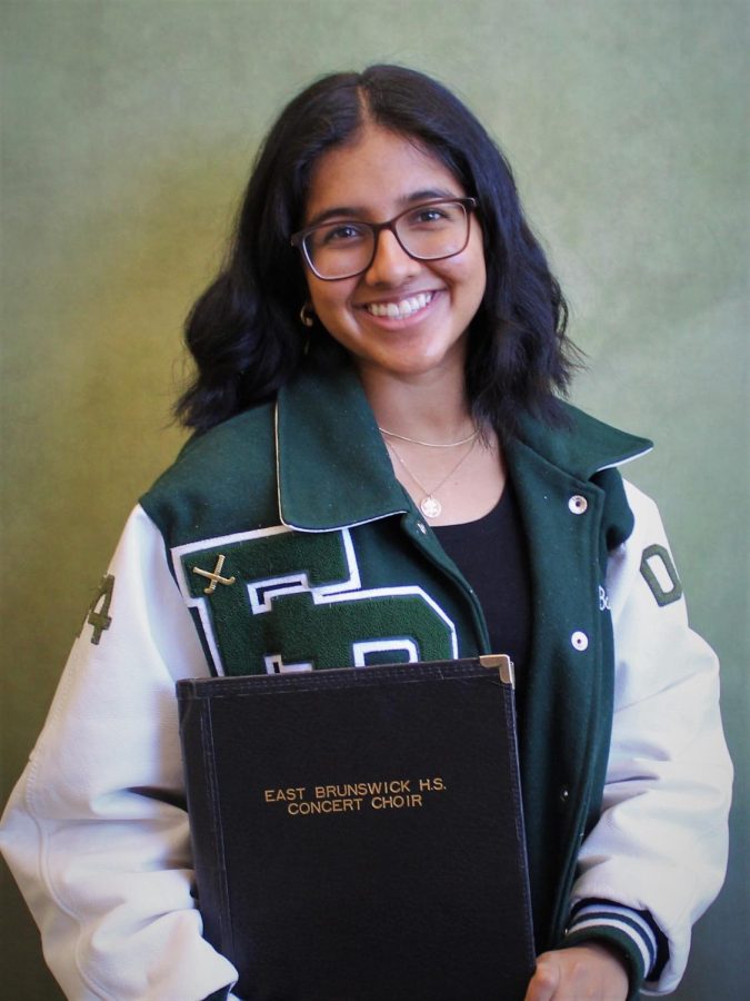 Barenya Das flashes a smile while proudly wearing her varsity field hockey jacket while holding her concert choir folder. 