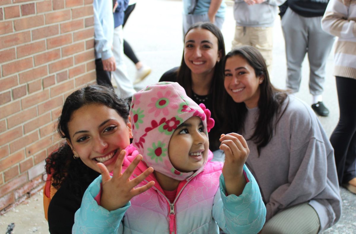 Seniors (from left) Maria Samaan, Amanda Beiderman, and Danielle Lederman pose for a picture with Avnoor, a preschool student, while waiting for her to be picked up.