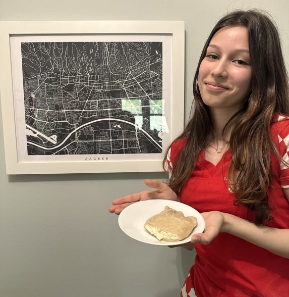 Mia captured next to a framed map of Zagreb in her kitchen, with homemade  štrukli. 
